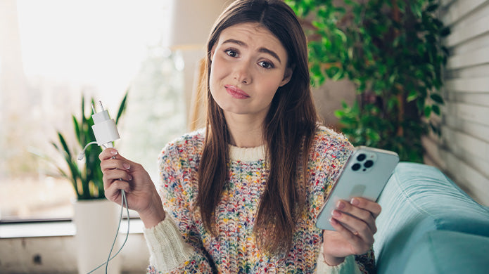 Mujer sosteniendo cargado de iPhone preguntándose como cuidar la batería del iPhone. 