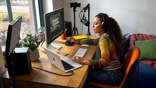 Una mujer trabajando en su escritorio y mostrando que es Macbook